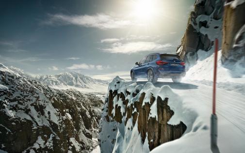 Blauer BMW X3 fährt in den Alpen