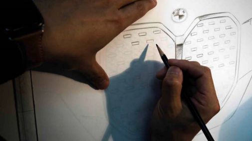 Männerhand hält Bleistift in der Hand und zeichnet die Front eines BMW
