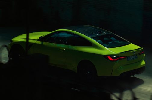 grünes BMW M4 Coupe fährt schnell - Seitenansicht 