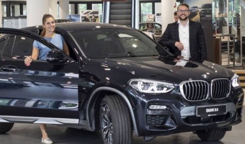 Verkäufer steht mit Mitarbeiterin am schwarzen BMW X4