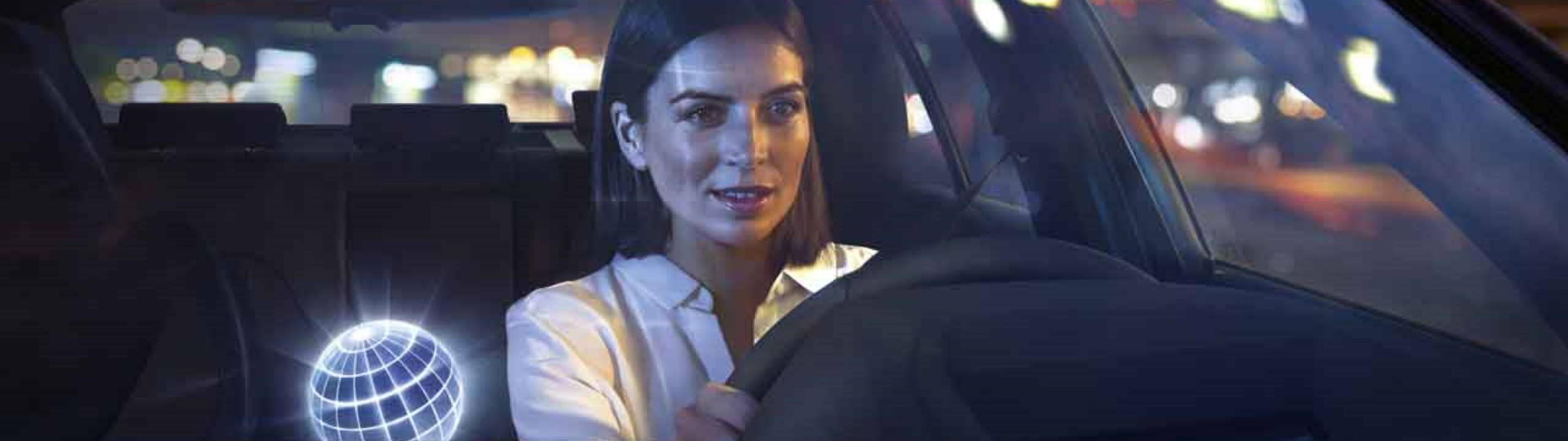Frau fährt bei Nacht in Ihrem BMW, eine virtuelle Kugel neben Ihr symbolisiert den BMW Personal Assistant