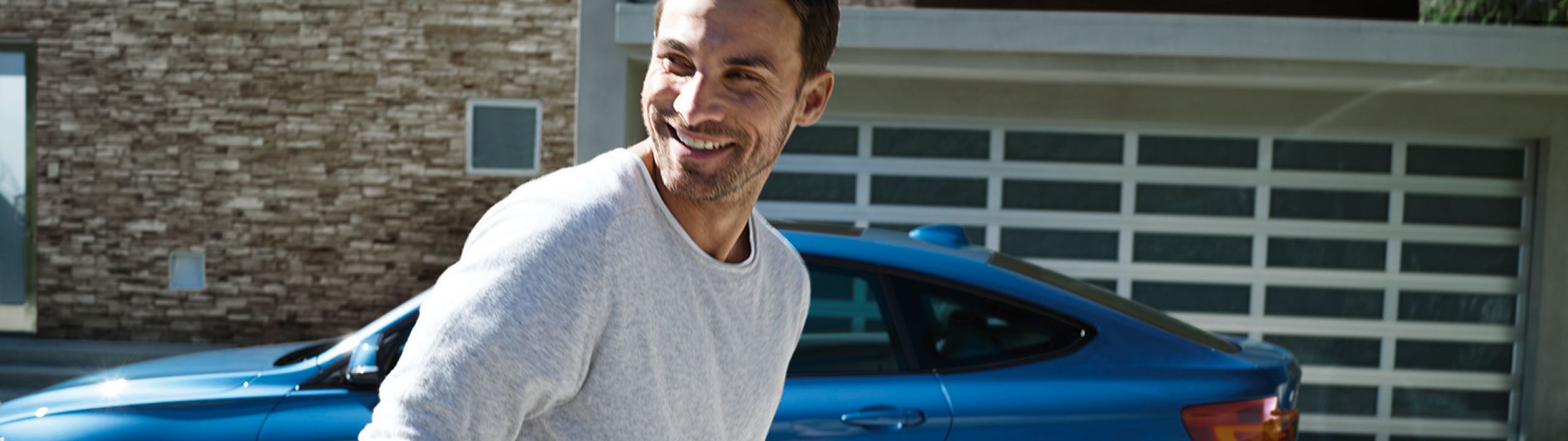 Mann lächelt - im Hintergrund ein blauer BMW